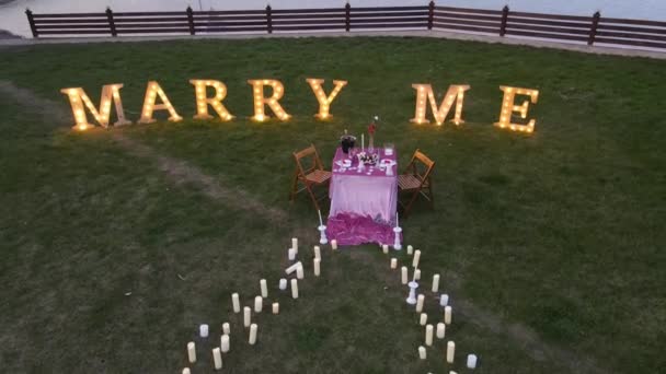 The setting of a romantic dinner in which there will be a marriage proposal, on the edge of the lake in nature. Inscription marry me. 4k concept — Stock Video