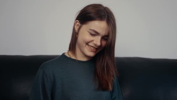 La chica pelirroja, hermosa, escribiendo concentrado y una amplia sonrisa un mensaje divertido, atrapado en la conversación con un buen estado de ánimo. Vestido con una maleta verde oscuro, sentado en un sofá negro. Concepto 4k — Vídeos de Stock