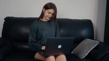 Kızıl saçlı, çilli genç bayan buna karşılık olarak bir mesaj veriyor, iyi bir ruh haliyle bir sohbete yakalanmış. Koyu yeşil bir bavul içinde, siyah bir koltukta oturuyor. 4k konsepti