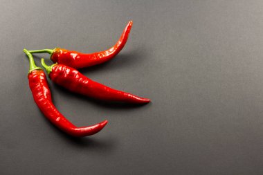  Koyu bir arka planda üç kırmızı kırmızı biber.