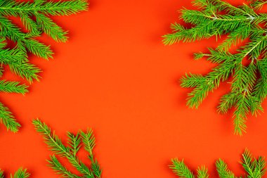 Noel kompozisyonu. Kırmızı arkaplanda köknar dallarından yapılmış Noel çerçevesi