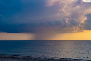 Kuzey denizi üzerinde yağmur bulutları, Danimarka, ufuk seviyesinin çok altında yel değirmenleri görünür.
