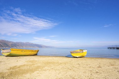 Kumsalda balıkçı teknesi. Sahildeki dağ arka planda