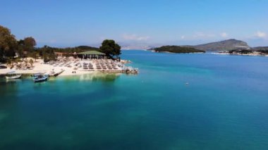Güneşli bir günde İyon Denizi 'nde güneşsiz güneşli bir sahilin havadan görünüşü. Kamera yavaşça döner. Ksamil, Arnavutluk.