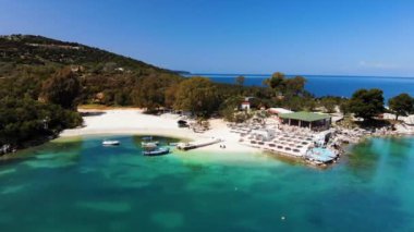 Güneşli bir günde İyon Denizi 'nde güneşsiz güneşli bir sahilin havadan görünüşü. Kamera yavaşça döner. Ksamil, Arnavutluk.