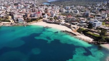 İyon Denizi 'nde güneşli bir günde insansız beyaz kumlu bir sahilin havadan görünüşü. Kamera yavaşça döner. Ksamil, Arnavutluk.