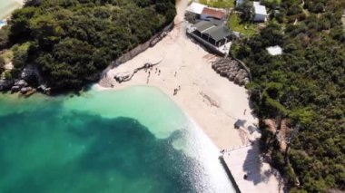 Beyaz kumlu bir plajın havadan görünüşü. İyon Denizi 'nde güneşli bir gün. Kamera yavaşça döner. Ksamil, Arnavutluk.