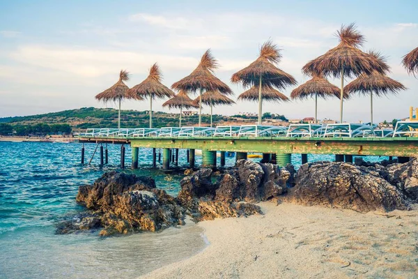 Cadeiras vazias sob guarda-chuvas de palha na praia em Albania — Fotografia de Stock