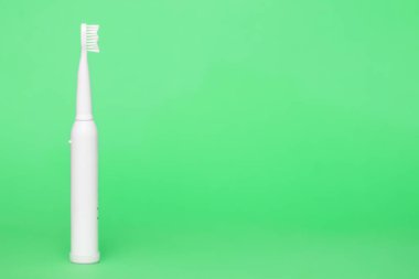 Açık yeşil arkaplanda beyaz kablosuz elektrikli diş fırçası, kopyalama alanı