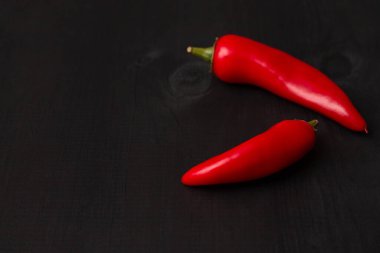 İki kapsül kırmızı biber siyah ahşap bir yüzey üzerinde, kopyala uzay