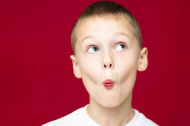 Beyaz tişörtlü çocuk 7-10, kırmızı arka planda öpüşme resmediyor.