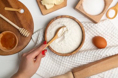 Pişirme malzemeleri. Tereyağı, şeker, yumurta, bal, soda, tuz ve bir kadının eli kaşığa un koyar. Düz yatıyordu.