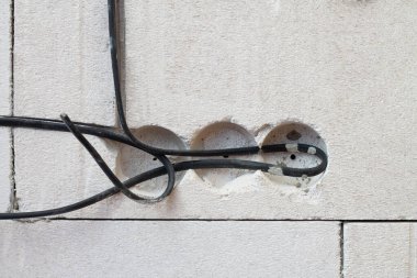 Elektrik prizleri için kabloları olan beton bloklardan yapılmış bir duvardaki delikler, bir ev inşa etme sürecinde
