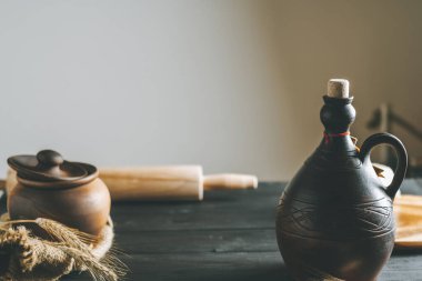 Yuvarlak toplu siyah tahta masa, çuval bezi, çivi, kil çömlek ve güneş ışığında yağ şişesi. Boşluğu kopyala