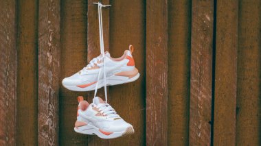 Beyaz kadınların spor ayakkabıları, üzerinde mercan parçaları olan kahverengi tahta duvarlarda asılı duran tahta çiviler. Pankart