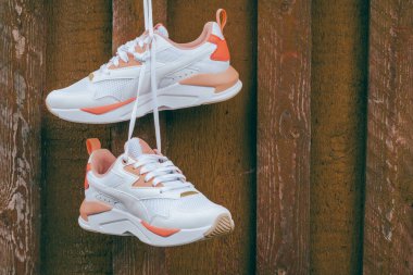 Beyaz kadınların spor ayakkabıları, mercan desenli kahverengi tahta duvarlara çivilenmiş.