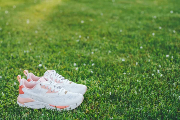 Λευκά Γυναικεία Αθλητικά Παπούτσια Κοραλλιογενή Ένθετα Στέκονται Στο Γρασίδι Ακτίνες — Φωτογραφία Αρχείου
