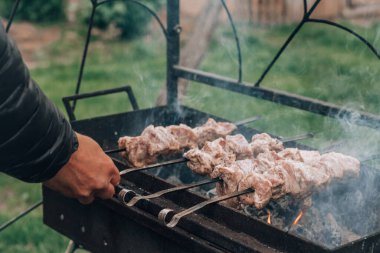 Erkek eli şişte çiğ ete dönüşür kömür ızgarasında pişirilir. Dışarıda barbekü yapmak.