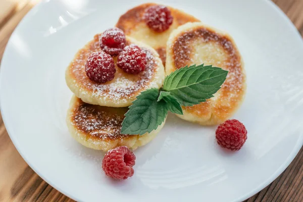 Νόστιμα Cheesecakes Τηγανίτες Πασπαλισμένες Άχνη Ζάχαρη Λευκό Πιάτο Ξύλινο Τραπέζι — Φωτογραφία Αρχείου