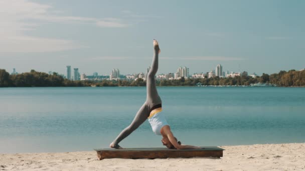 Mujer joven está haciendo ejercicio de yoga profesional en la playa . — Vídeos de Stock