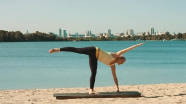 Genç kadın sahilde profesyonel yoga egzersiz yapıyor.