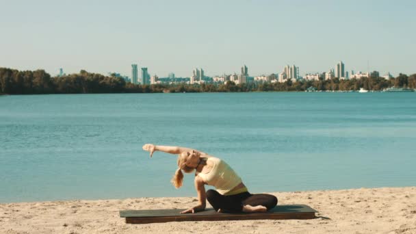 Jonge vrouw doet professionele yoga training op het strand. — Stockvideo