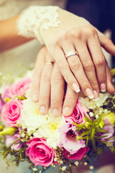 Handen en ringen op bruiloftsboeket — Stockfoto