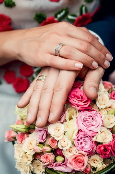 Hände und Ringe am Brautstrauß Stockbild
