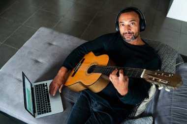 Yakışıklı adam gitar çalmayı öğrenmek için online kursa gidiyor.