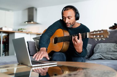 40 yaşında bir adam evde online derslerle gitar öğreniyor.
