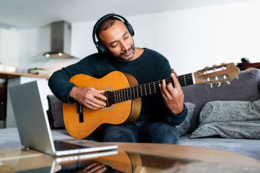 40 yaşında bir adam evde online derslerle gitar öğreniyor.