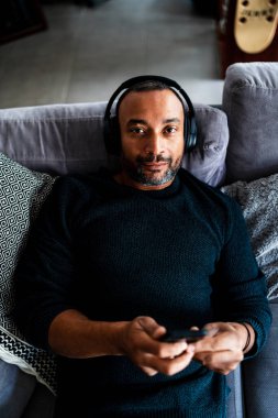 Karışık ırk adamı evde dinleniyor ve müzik dinliyor.