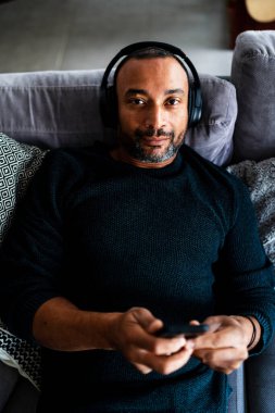 Orta yaşlı bir adam evinde kanepede dinleniyor.