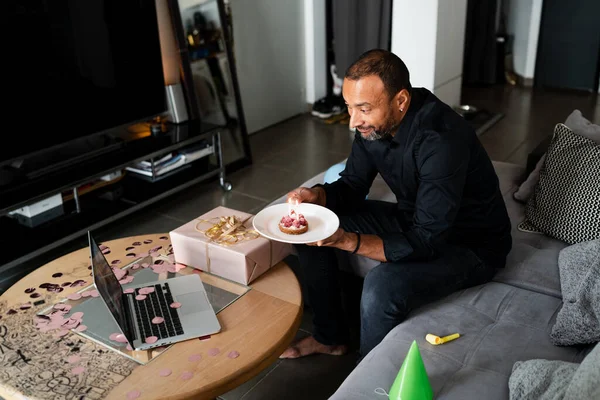 Virus pandemic and social impact: 40 years old man celebrating his birthday at home using his computer to talk to his family