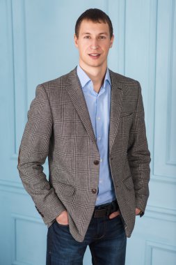 Üzerinde mavi bir backgrou ayakta zeki bir genç adam portresi