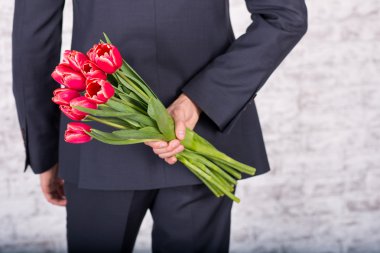 Çiçekler beyaz arka plan üzerinde tutarak gülümseyen iş adamı. Bouq