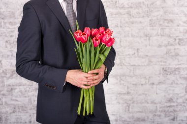 Çiçekler beyaz arka plan üzerinde tutarak gülümseyen iş adamı. Bouq