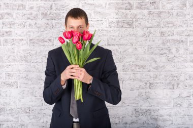 Çiçekler beyaz arka plan üzerinde tutarak gülümseyen iş adamı. Bouq