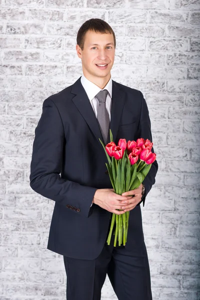 Smiling businessman holding flowers over white background — Stock Photo, Image