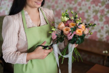 Bir düğün için bir buket gül tutan kadın çiçekçi