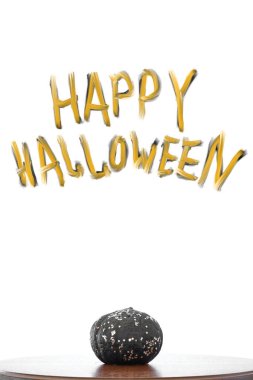 Beyaz bir arkaplan önünde ahşap taburede parıltılı siyah balkabağı.