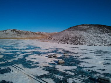 a drone view of old Soviet cars standing on the ice of Lake Baikal near the shore of Olkhon Island. Travel through winter Siberia Russia. clipart
