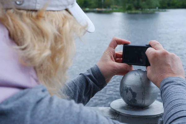 Una chica con una gorra blanca toma fotos del paisaje acuático con una cámara. Día de San Veronicas Día de los Fotógrafos . — Foto de Stock