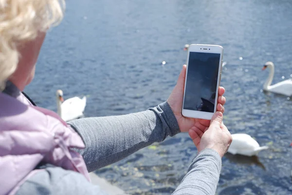 Una chica con gorra blanca fotografía el paisaje acuático por teléfono. Día de San Veronicas Día de los Fotógrafos . — Foto de Stock