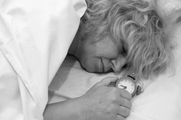 Mujer acostada en la cama mirando el despertador. —  Fotos de Stock