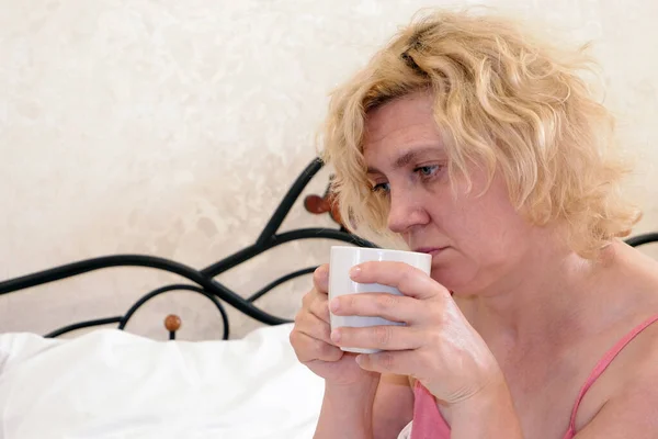 Una mujer después de despertarse del sueño tiene una taza de café o té en sus manos. —  Fotos de Stock