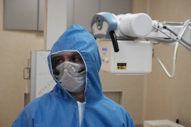 Röntgen odasında antiviral tulumlar giyen bir radyologun çalışması..