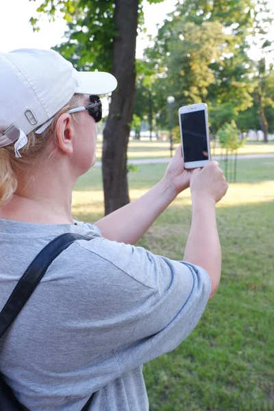 Una turista con gorra blanca está tomando una foto por teléfono.. — Foto de Stock