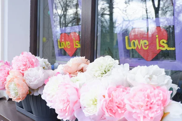 Wit-roze pioenroos knoppen op de vensterbank tegen de achtergrond van de inscriptie liefde is. — Stockfoto