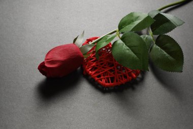 Kırmızı kalp ve kırmızı gül koyu arkaplanda.